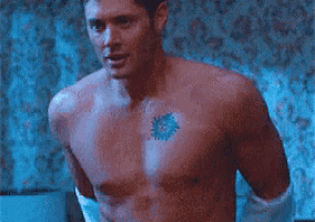 a shirtless man with a tattoo on his chest is holding a towel in his hand .
