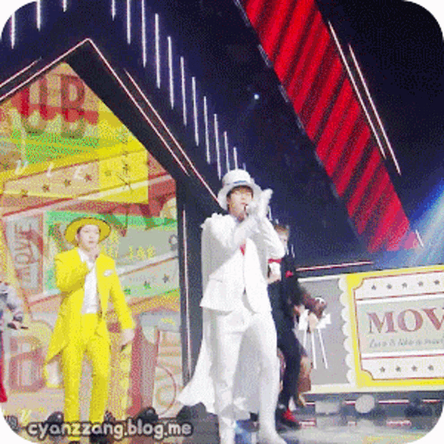 a man in a white suit stands in front of a sign that says move