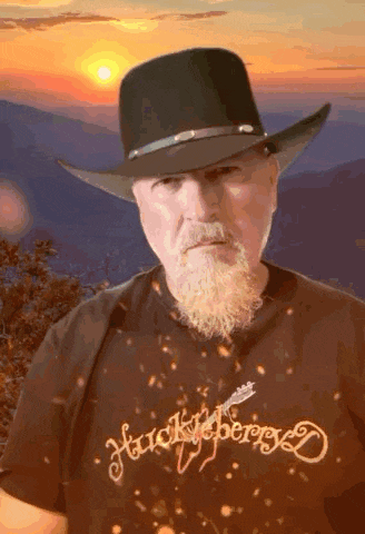 a man with a beard wearing a cowboy hat and a shirt that says huckleberry