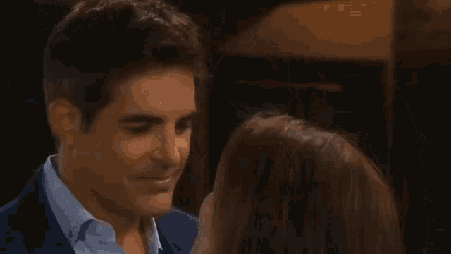 a man in a suit is kissing a woman on the cheek .