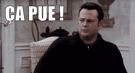 a man is sitting in a chair in a living room with the words `` ca pue ! '' written above him .