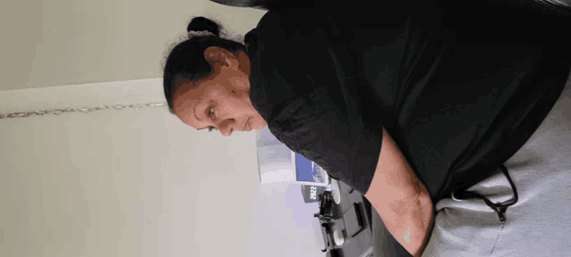 a woman in a black t-shirt looks down at something