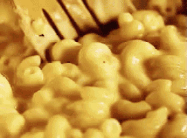 a close up of macaroni and cheese being stirred with a fork