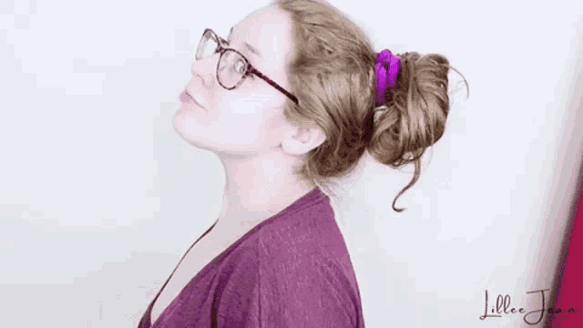 a woman with glasses and a bun in her hair is looking up .