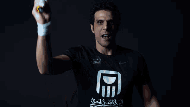 a man holding a tennis racquet with a black shirt that says black ball
