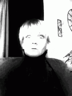 a black and white photo of a woman sitting on a couch making a funny face .