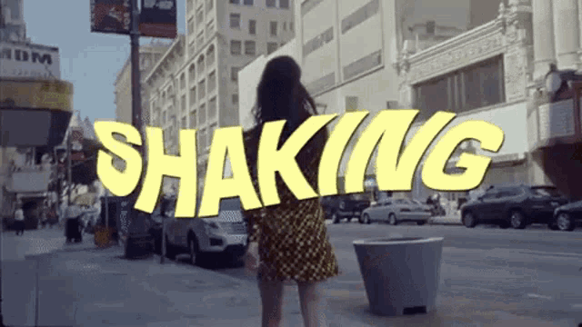 a woman walking down a street with the word shaking written in yellow