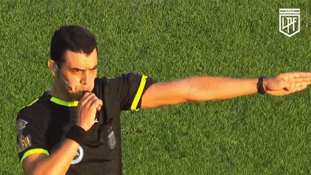 a referee is blowing a whistle while wearing a shirt that says lpfl on it