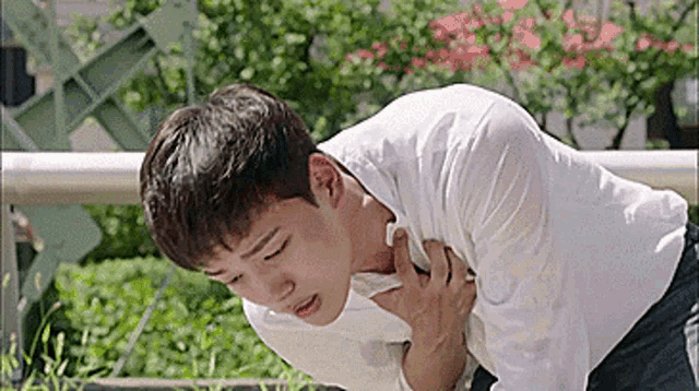 a man is holding his chest in pain while laying on the ground .