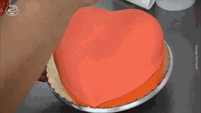 a heart shaped cake is being decorated with chocolate frosting