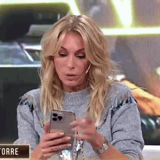 a woman in a sweater is looking at her phone