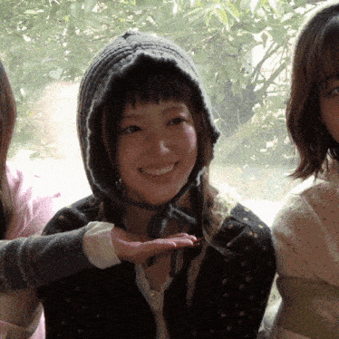 a woman wearing a knitted hat is smiling and holding her hand out