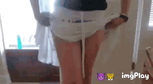 a woman in a diaper is standing in a room with a window .