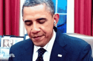 barack obama is wearing ear buds while sitting in front of a window .