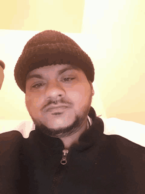 a man wearing a black hat and a black jacket with a zipper