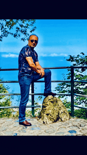 a man sitting on top of a rock with his leg up
