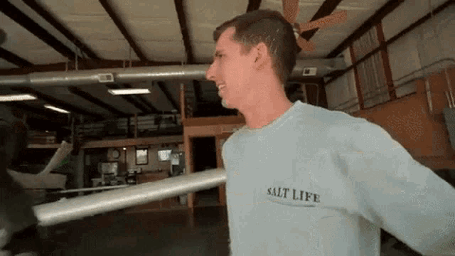 a man wearing a salt life shirt is holding a metal bar