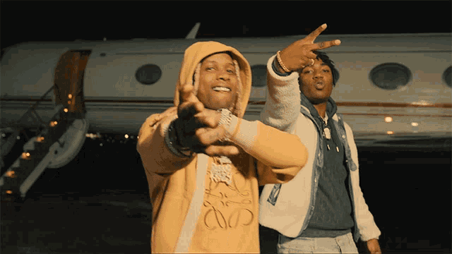 two men are standing in front of an airplane and one of them is wearing a hoodie that says loewe on it
