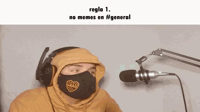 a man wearing a mask and headphones stands in front of a microphone and says regla 1 no memes en #general