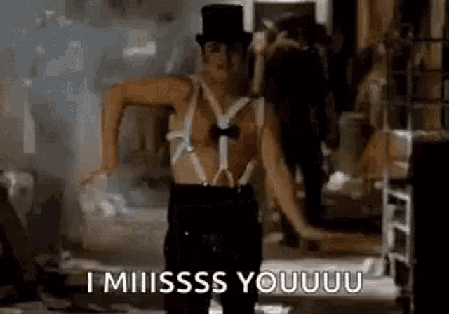 a man in a top hat and suspenders is dancing in a dark room .