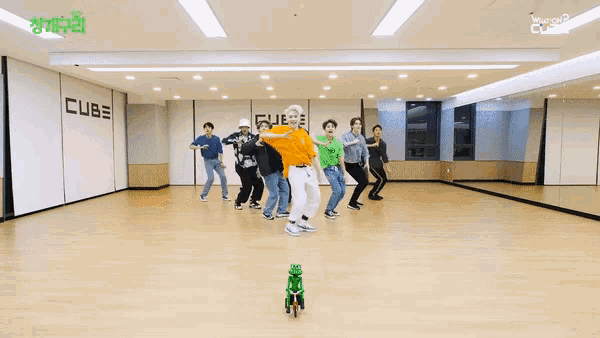a group of people are dancing in a room with the word cube on the wall behind them
