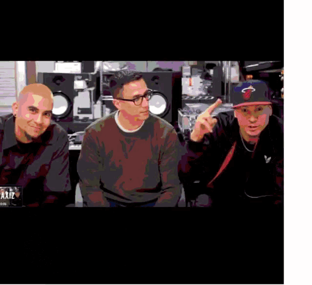 three men are posing for a picture and one has a hat with the miami heat logo on it