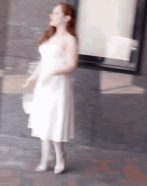 a woman in a white dress is standing on a sidewalk