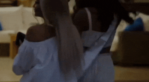 two women in white dresses are dancing together in a room .