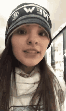 a woman wearing a beanie with the word mem on it is smiling