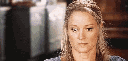 a woman in a blue sweater is making a serious face .