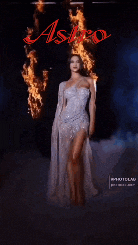 a woman in a white dress is standing in front of a fire and the word astro