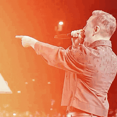 a man singing into a microphone with his finger pointing