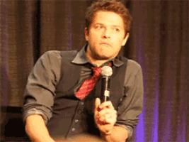 a man in a vest and tie is holding a microphone in his hand