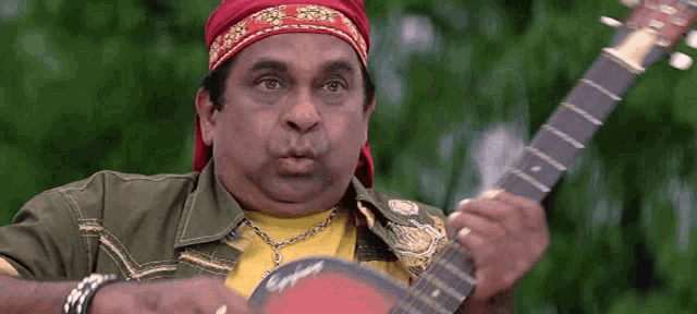 a man wearing a red headband is playing a guitar .
