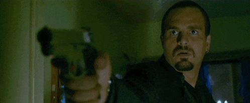a man with a beard is holding a gun in his right hand