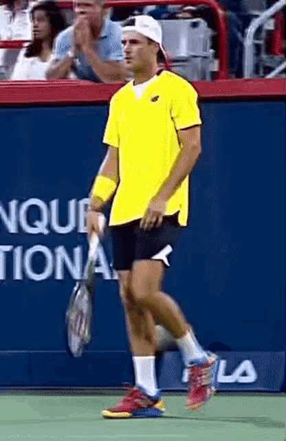 a man in a yellow shirt holds a tennis racquet