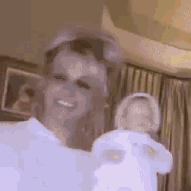 a woman is holding a baby doll in her arms and smiling in a room .