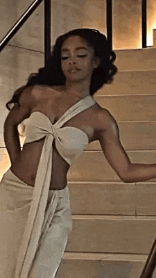 a woman in a white dress is standing on stairs .
