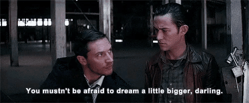 two men are standing next to each other in a dark room and one of them is talking to the other .