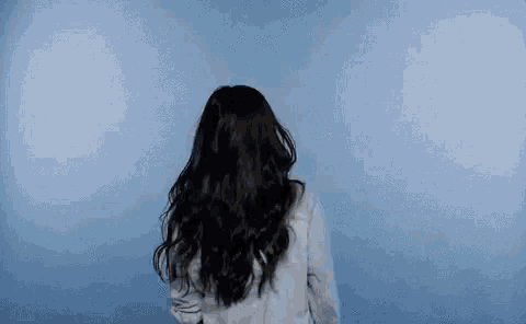 the woman is wearing a white shirt and has long black hair .