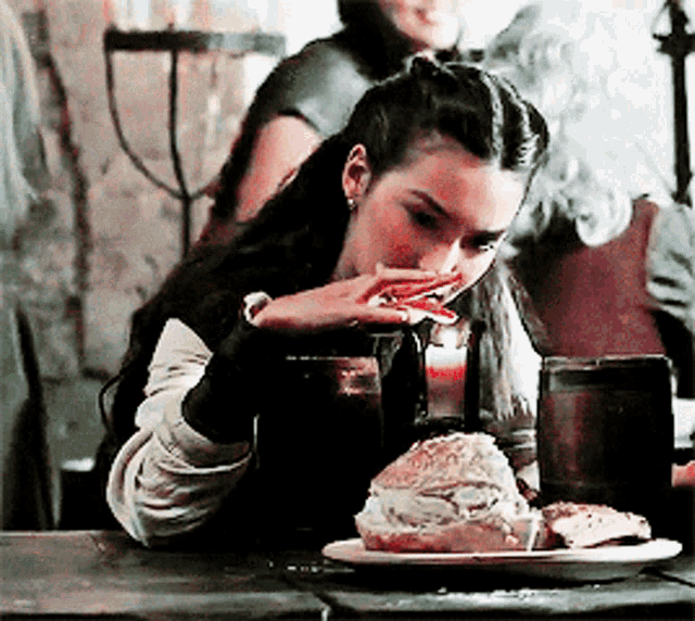 a woman is sitting at a table with a plate of food and a glass of beer