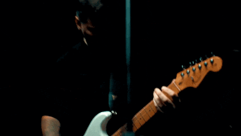 a man with a tattoo on his arm plays an electric guitar