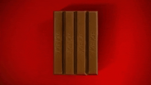 a man in a tuxedo is coming out of a kit kat box .