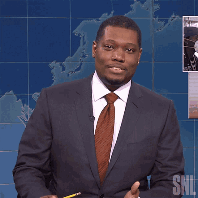 a man in a suit and tie holds a pencil in front of a sign that says snl