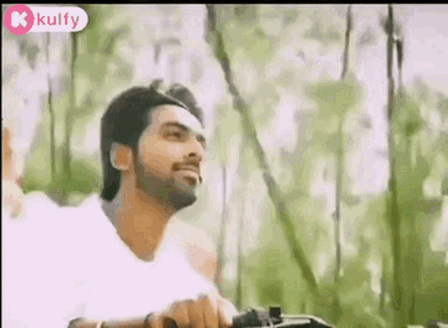 a man with a beard is riding a bike through a forest .