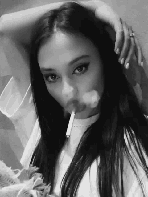 a woman is smoking a cigarette with smoke coming out of her mouth