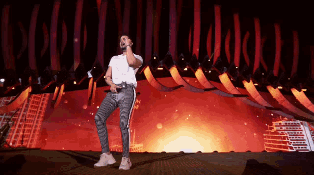 a man singing into a microphone in front of a red background