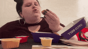 a woman sitting at a table with a box of taco bell in front of her
