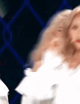 a woman in a white dress is dancing in front of a blue fence .