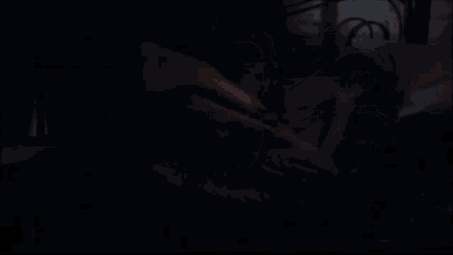 a woman in a black tank top is standing in the dark with her mouth open